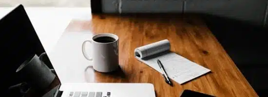 ordinateur, bloc notes, téléphone et mug de café sur une table en bois